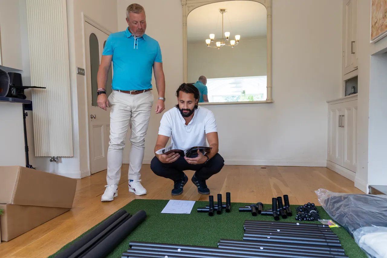 Deux techniciens préparent le kit d'une enclosure SimSpace posé au sol d'un salon avant montage